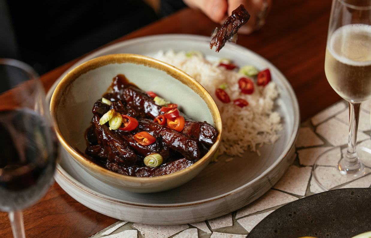 A meat and rice dish on a table with drinks