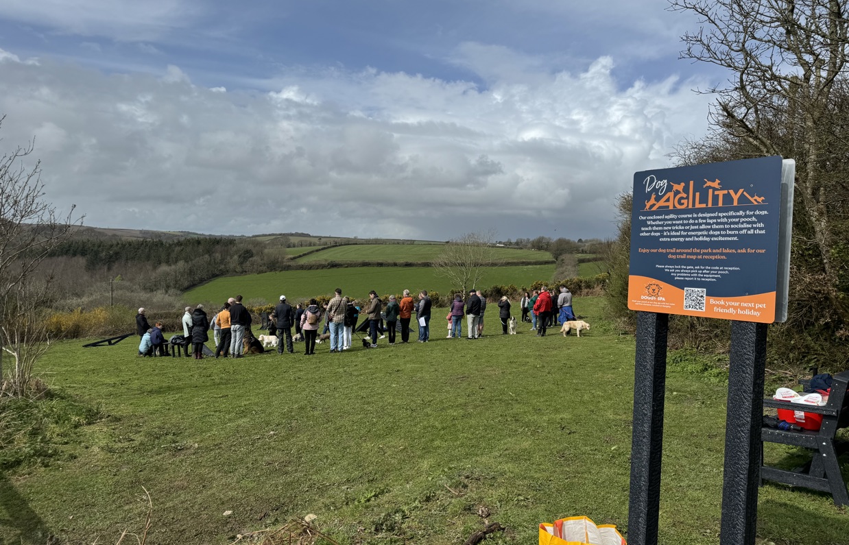 A group of people with dogs in a dog agility field for a Trufts Dog Show at Tregoad Holiday Park