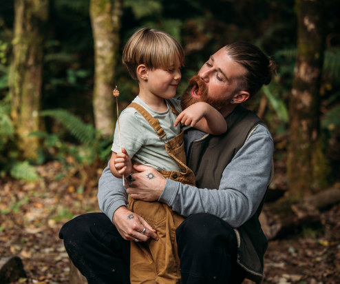 A man and a young boy in the woods with toasted marshmallows