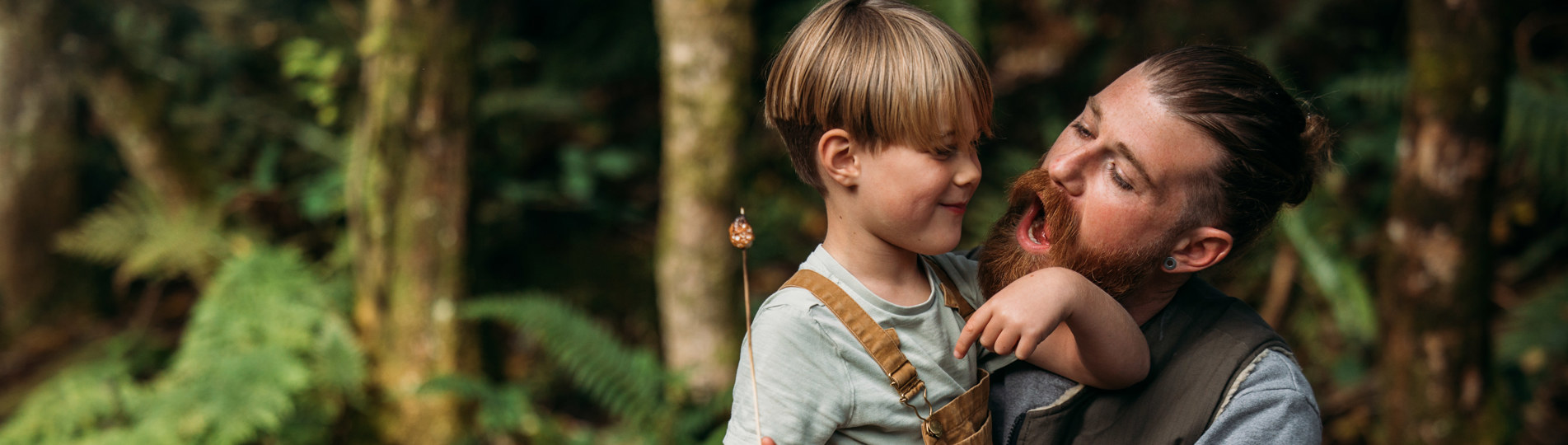 A man and a young boy in the woods with toasted marshmallows