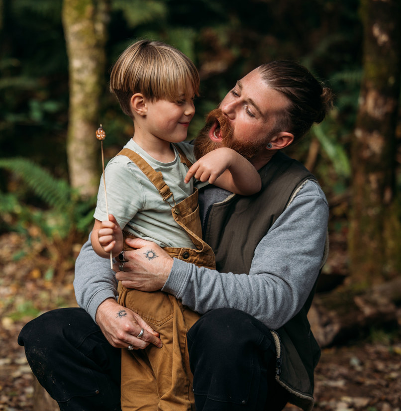 A man and a young boy in the woods with toasted marshmallows