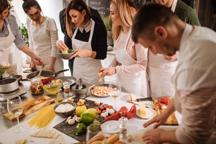 A selection of dishes on a table with a group of people wearing aprons surrounding it