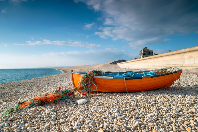 A shingle beach with a boat on the stones
