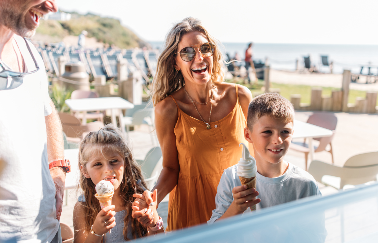 A family of four at a dessert bar smiling with ice creams in the children's hands