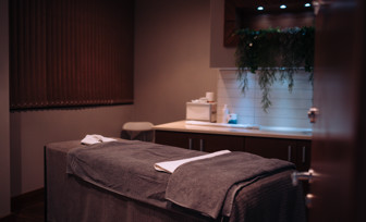 A spa treatment room with bed, products and cosy, calming decór