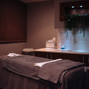 A spa treatment room with bed, products and cosy, calming decór