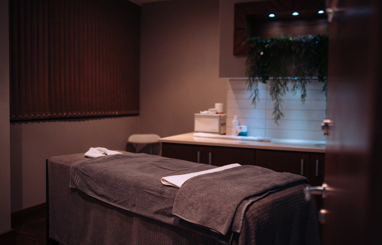 A spa treatment room with bed, products and cosy, calming decór