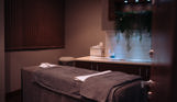 A spa treatment room with bed, products and cosy, calming decór