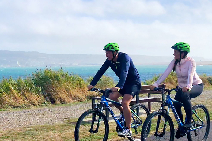 A couple cycling along a coastal trail