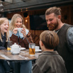 A family of four sat at a high outdoor table having a drink