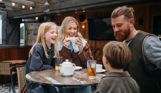 A family of four sat at a high outdoor table having a drink