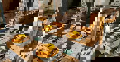 Open Plan Living area with dining table laid for four people and the lounge and breakfast bar behind it