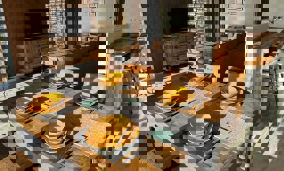 Open Plan Living area with dining table laid for four people and the lounge and breakfast bar behind it