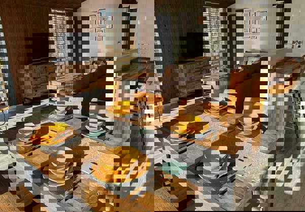 Open Plan Living area with dining table laid for four people and the lounge and breakfast bar behind it