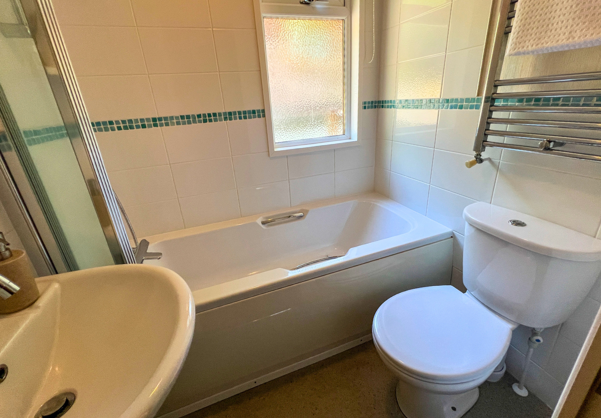 Internal of a lodge bathroom with shower over bath, sink and toilet