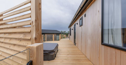 External of a luxury lodge on pitch with decking and hot tub
