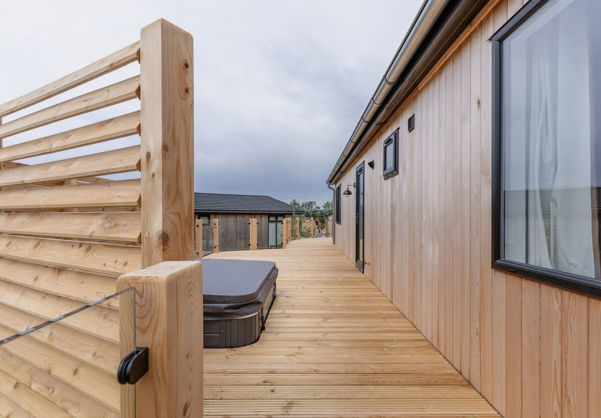 External of a luxury lodge on pitch with decking and hot tub