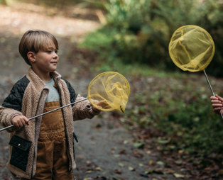 A young boy with a fishing net in the woods