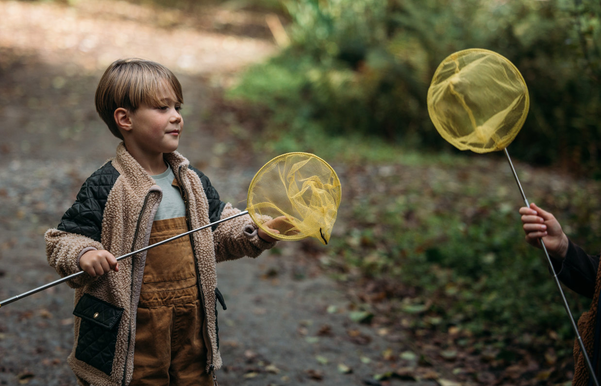 A young boy with a fishing net in the woods