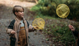 A young boy with a fishing net in the woods