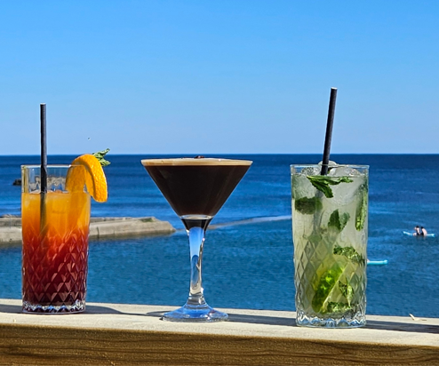 A variety of cocktails on a table with the sea as the backdrop