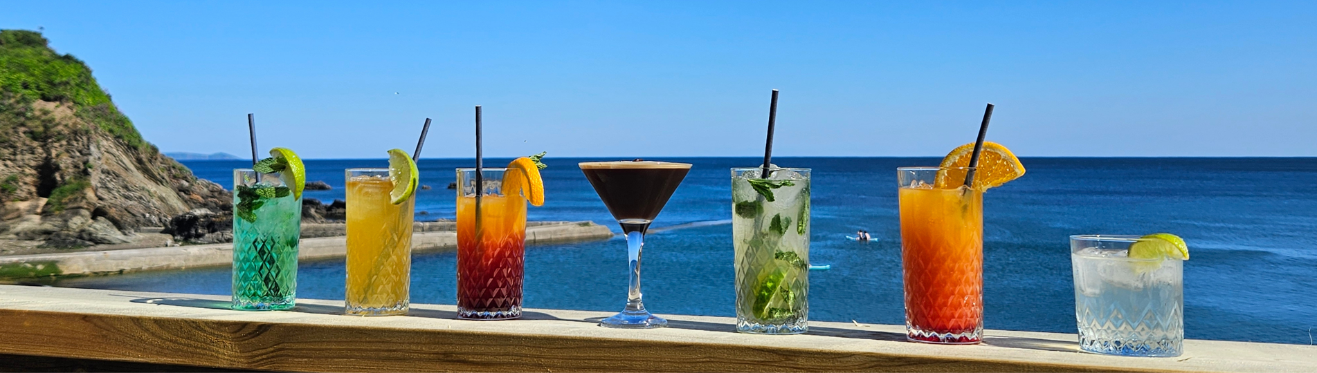 A variety of cocktails on a table with the sea as the backdrop
