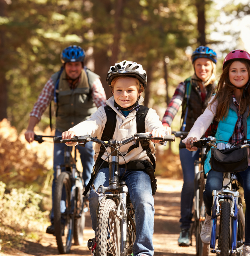 A family of four cycling through woodland