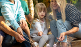 A family of four toasting marshmallows on the fire among woodland