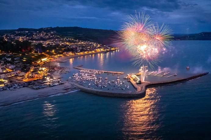 A small coastal harbour town at night with fireworks