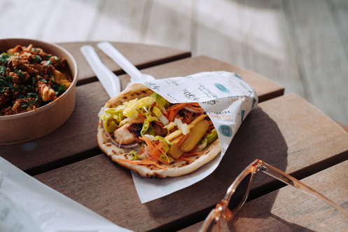A gyros and box of loaded fries on a table with sunglasses