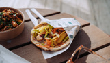 A gyros and box of loaded fries on a table with sunglasses