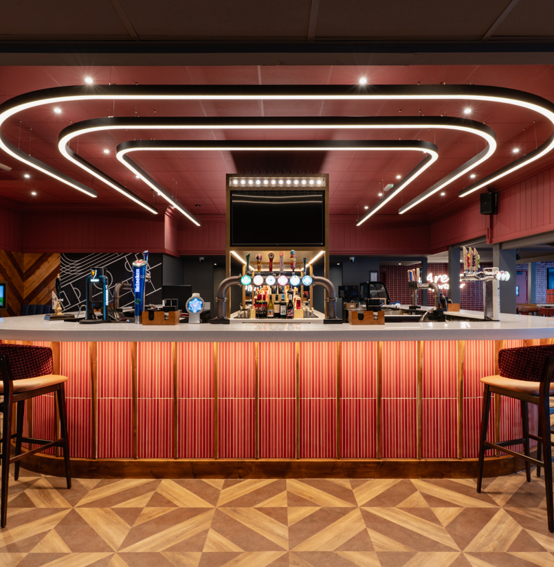 Internal of the Arena Sports Bar striking U-shaped bar with bar stools and dramatic lighting