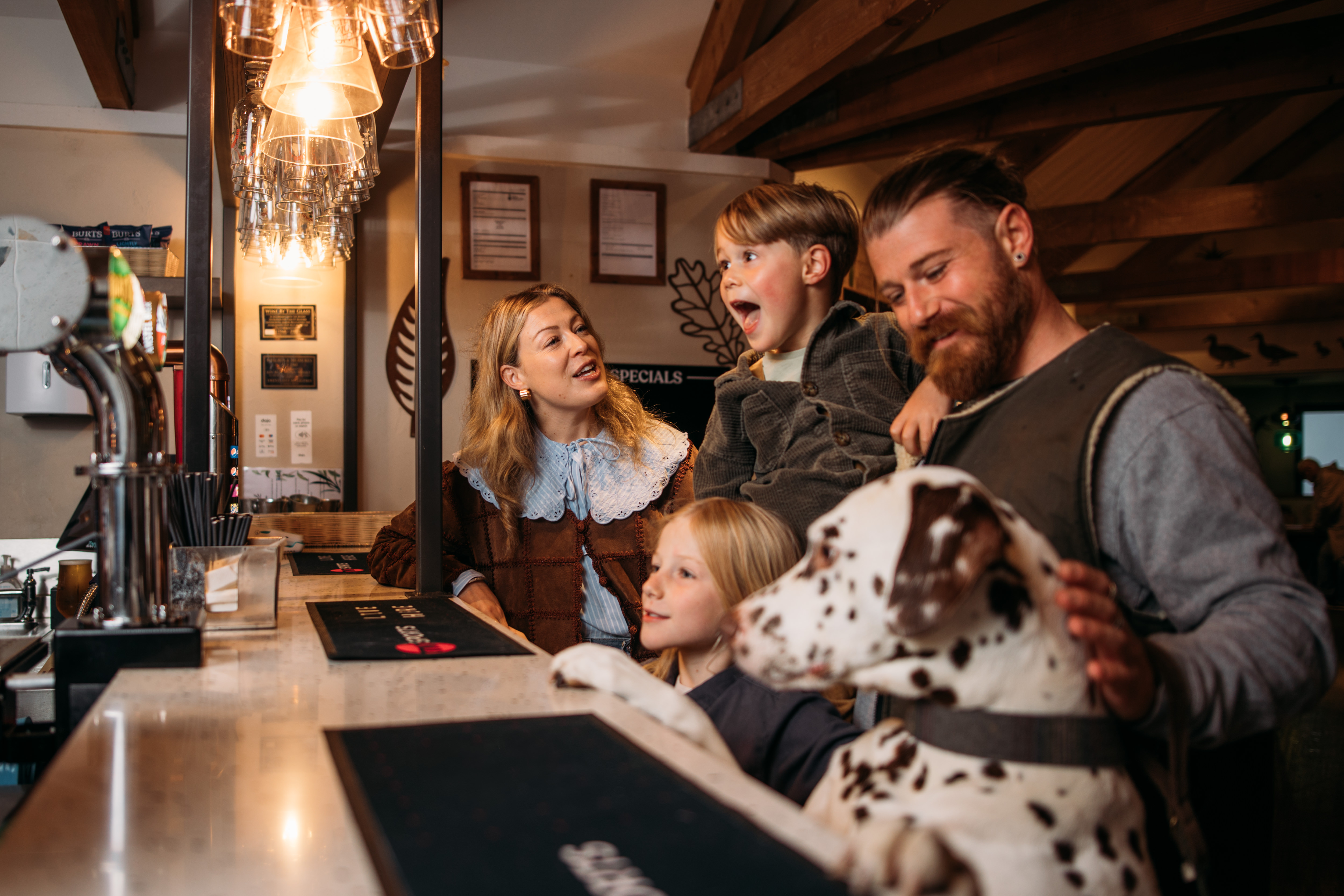 A family of four stood at the bar in Stargazy Bar & Grill with a dalmatian stood up on its back legs