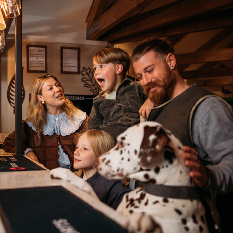 A family of four stood at the bar in Stargazy Bar & Grill with a dalmatian stood up on its back legs