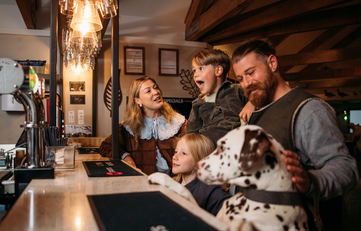 A family of four stood at the bar in Stargazy Bar & Grill with a dalmatian stood up on its back legs