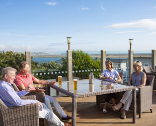 Breeze Bar & Grill Terrace with two men and two women sat around a table with seaviews and drinks