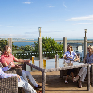 Breeze Bar & Grill Terrace with two men and two women sat around a table with seaviews and drinks