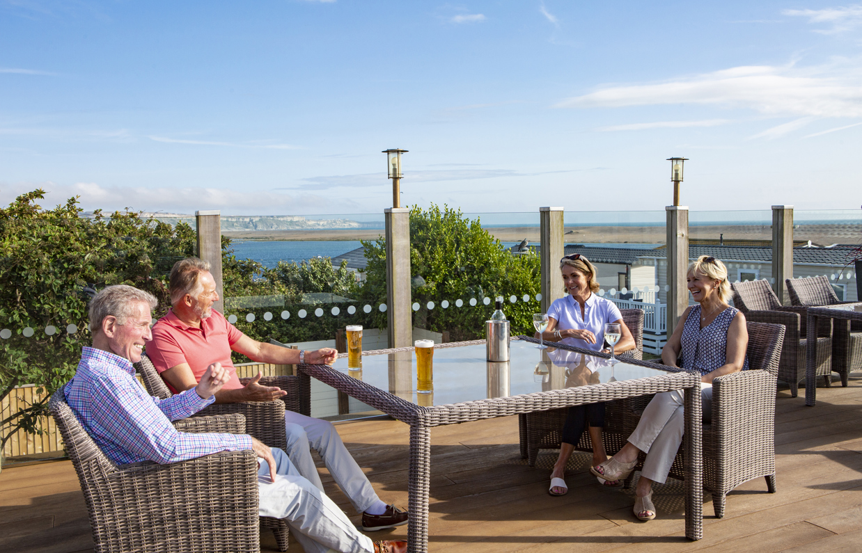 Breeze Bar & Grill Terrace with two men and two women sat around a table with seaviews and drinks