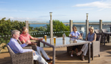 Breeze Bar & Grill Terrace with two men and two women sat around a table with seaviews and drinks