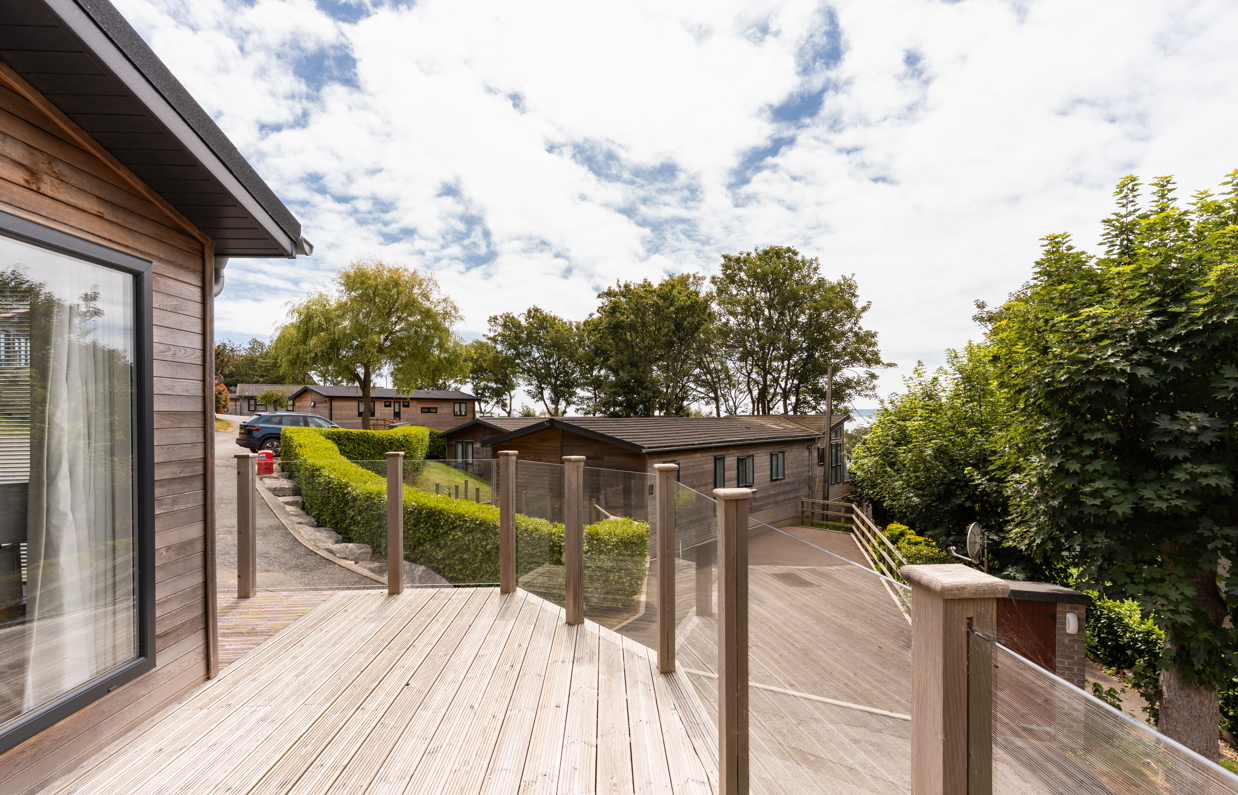 The view from the Kingfisher area of Osmington Mills Lodge Park surrounded by lodges and trees on a sunny day