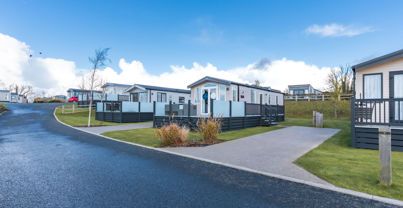 External of a caravan on pitch with decking and a parking space 