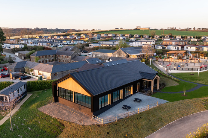 Aerial view of an indoor heated swimming pool within a barn style building with boho-chic styling and countryside views