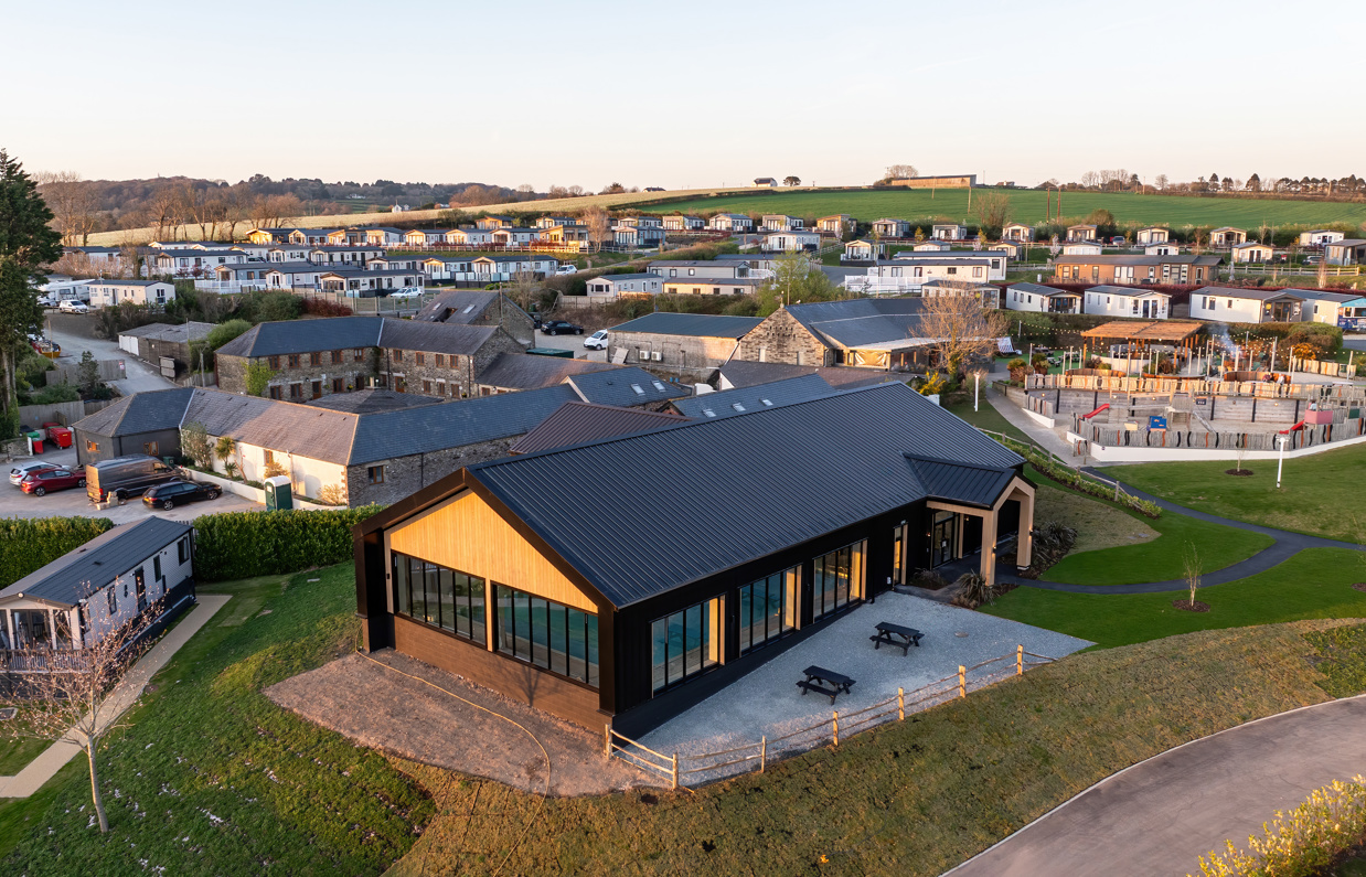 Aerial view of an indoor heated swimming pool within a barn style building with boho-chic styling and countryside views