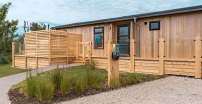 External of a luxury lodge on pitch with decking and EV charger