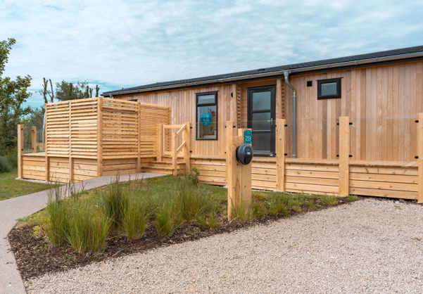 External of a luxury lodge on pitch with decking and EV charger