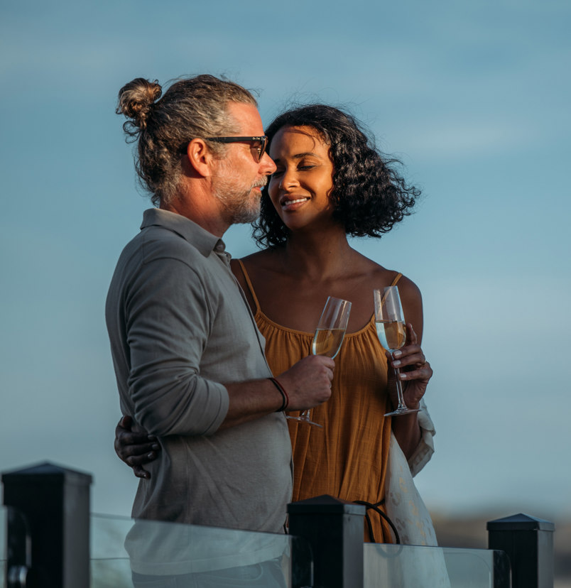 Couple celebrating on deck of holiday home overlooking chesil beach