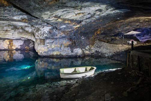 Underground caves lit up with water within them and small boats
