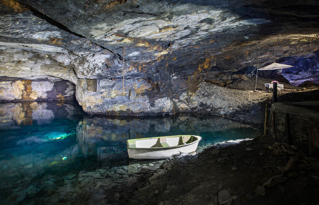Underground caves lit up with water within them and small boats