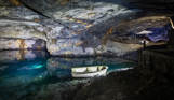 Underground caves lit up with water within them and small boats
