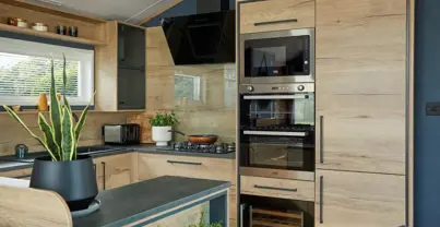 Modern kitchen and breakfast bar fitted with contemporary natural wood cupboard doors and dark blue walls